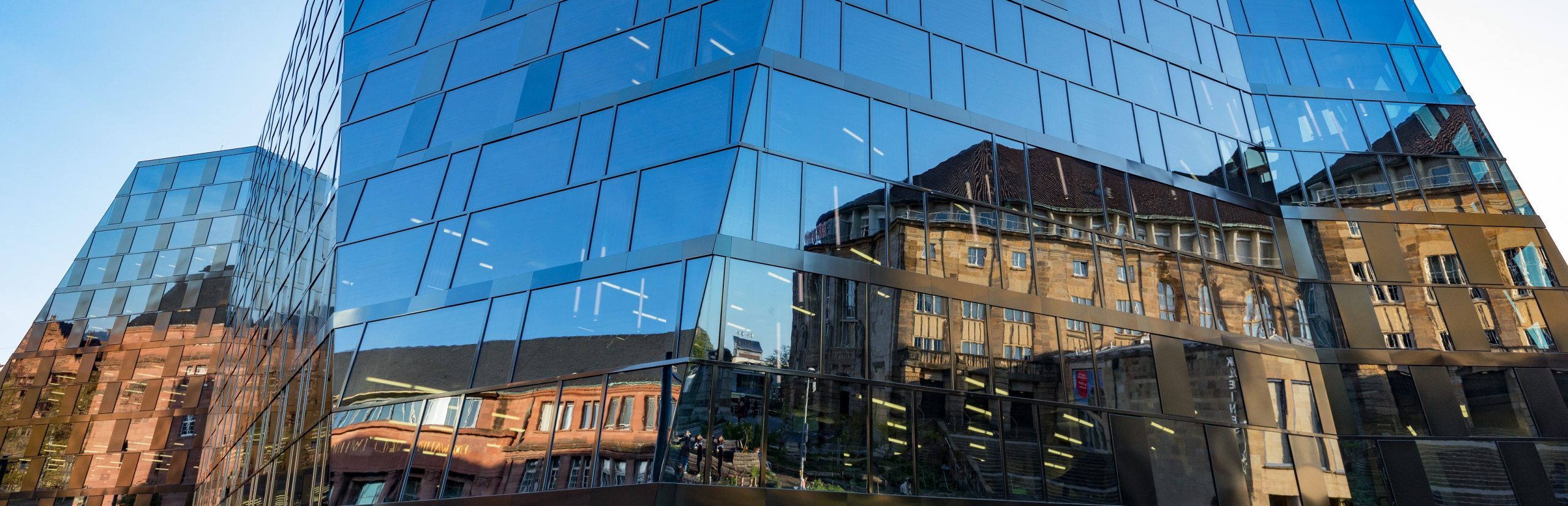 Spiegelung der Alten Universität und des Stadttheaters an der Außenfassade der neuen Universitätsbibliothek.